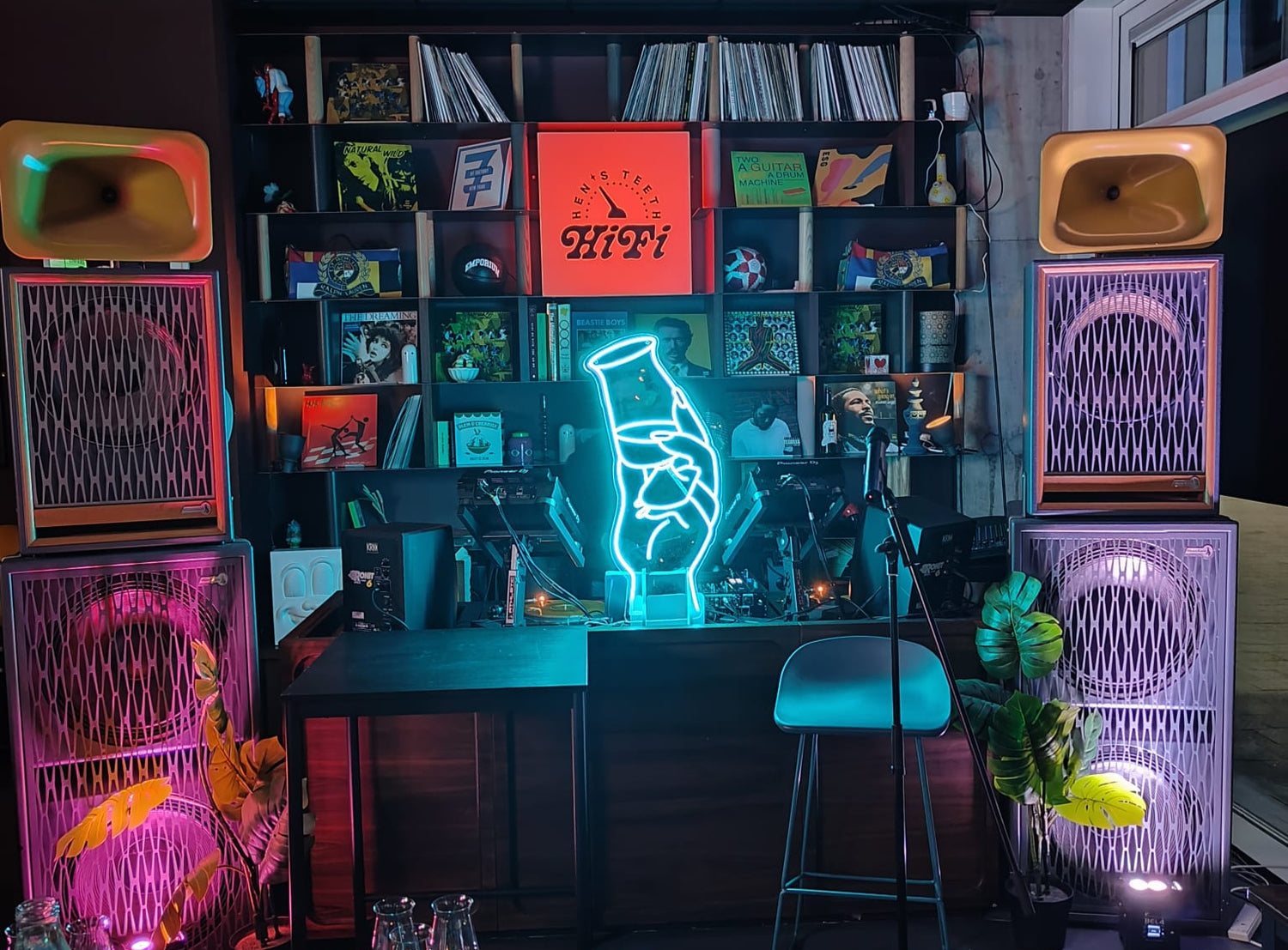Neon-lit room with record player, books, and a hand gesture light.